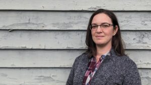 Sarah Taber in front of an older home exterior wall