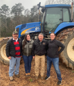 Sarah standing with farmers in front of a blue tractor